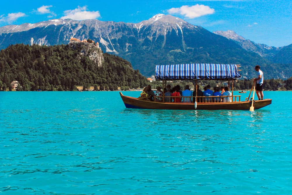 people on boat on lake near mountain during daytime