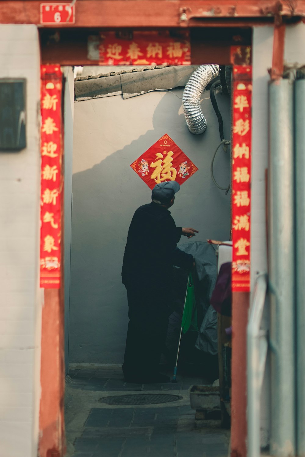 man in black thobe standing near red and white wall