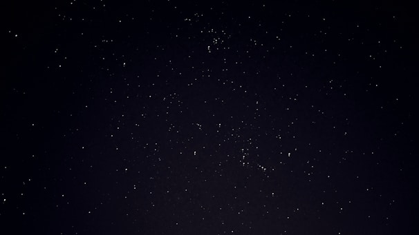 A serene night sky filled with stars forming a glowing zodiac wheel.