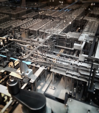 A complex network of mechanical gears and components, featuring metallic structures and various intricate parts aligned in a precise, orderly fashion.