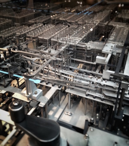 A complex network of mechanical gears and components, featuring metallic structures and various intricate parts aligned in a precise, orderly fashion.