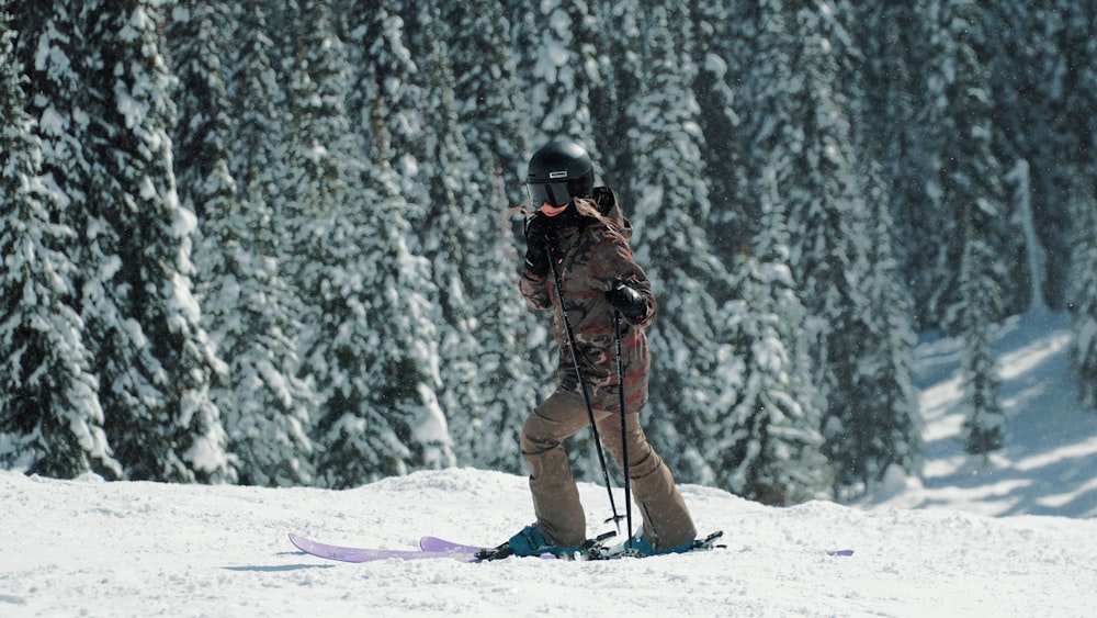 uomo in giacca marrone e pantaloni marroni che cavalcano su slitta da neve su terreno coperto di neve durante
