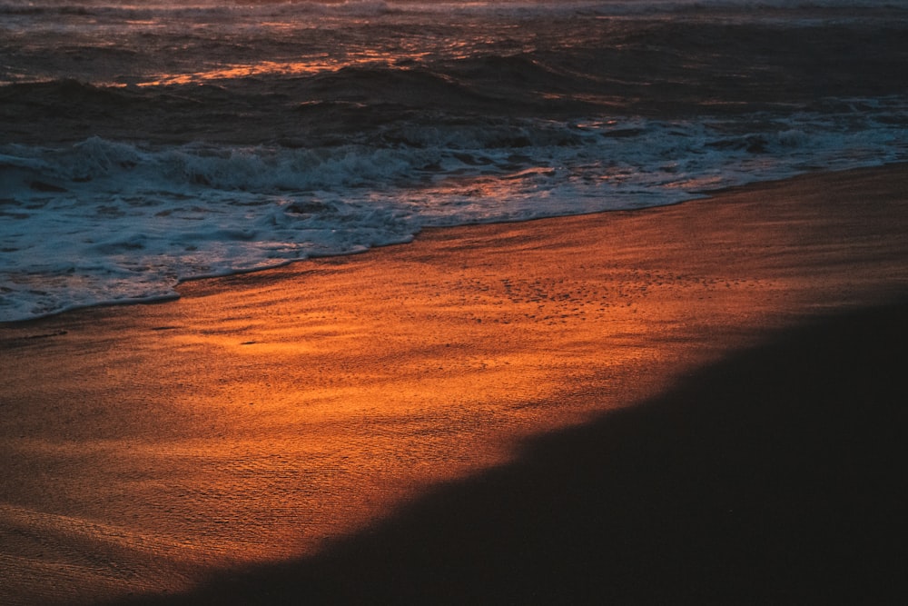 ocean waves crashing on shore during sunset