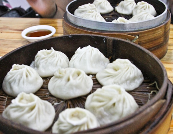 Golden fried dumplings arranged neatly on a bamboo steamer with dipping sauce on the side