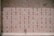 A wall composed of multiple small, marble plaques, each engraved with an emblem and inscription. Some plaques display small, decorative symbols and arrangements of letters, while others are marked with crosses and floral elements. A single bouquet of flowers rests at the bottom right corner.