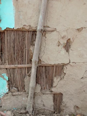 Close-up of a rustic wall decorated with cow dung and bamboo eco-friendly art elements in warm earthy tones.