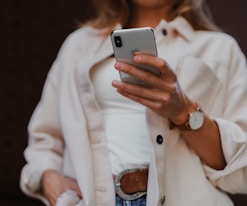 woman in white coat holding silver iphone 6
