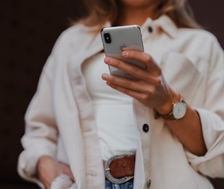 woman in white coat holding silver iphone 6