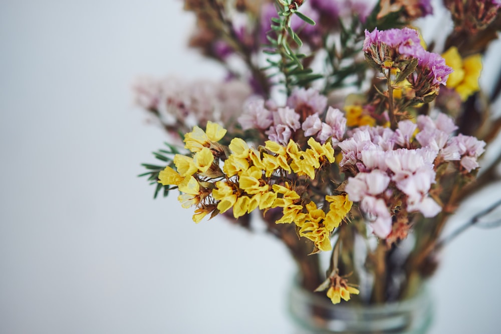 yellow and purple flowers in clear glass vase