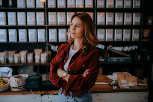Smiling woman holding a package with custom adhesive labels in a cozy store setting.