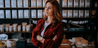 woman in brown jacket standing near black computer monitor