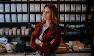 woman in brown jacket standing near black computer monitor