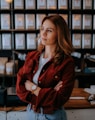 woman in brown jacket standing near black computer monitor