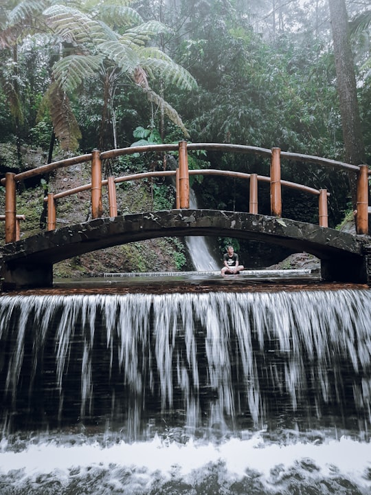 brown wooden bridge over water falls in Majalengka Indonesia