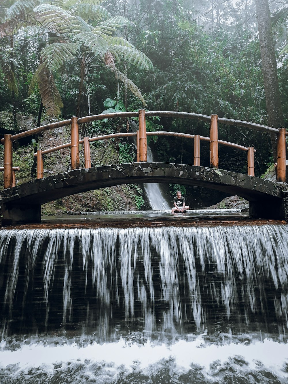 brown wooden bridge over water falls