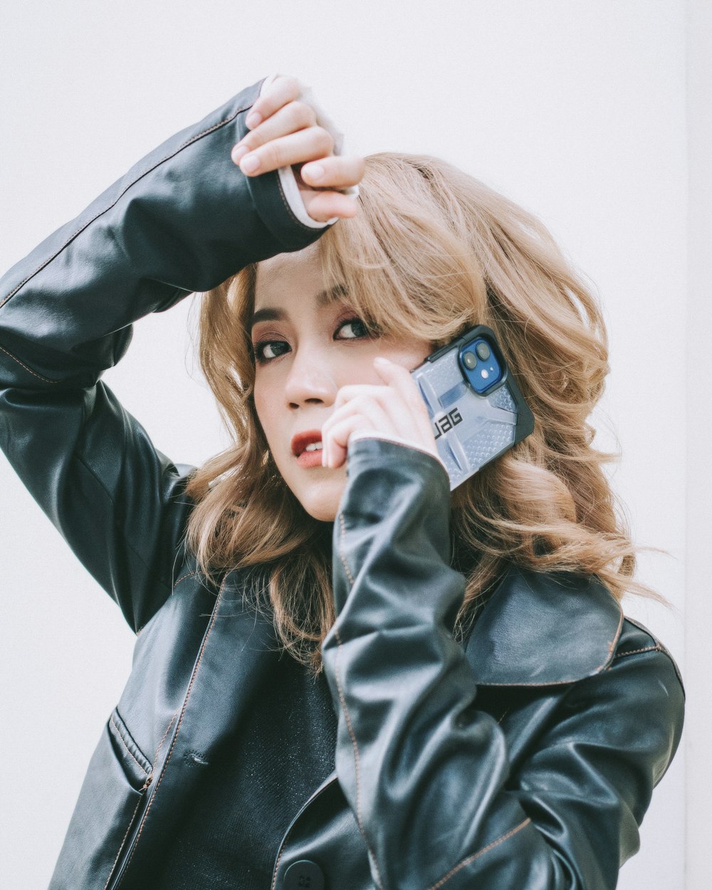 woman in black leather jacket holding blue and white ceramic mug