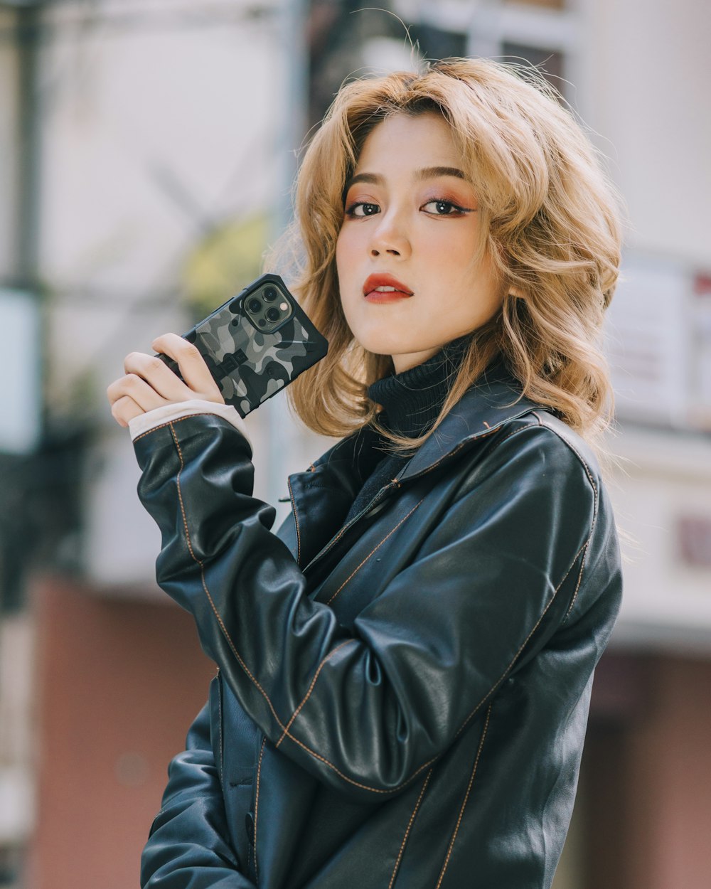 woman in black leather jacket holding black smartphone