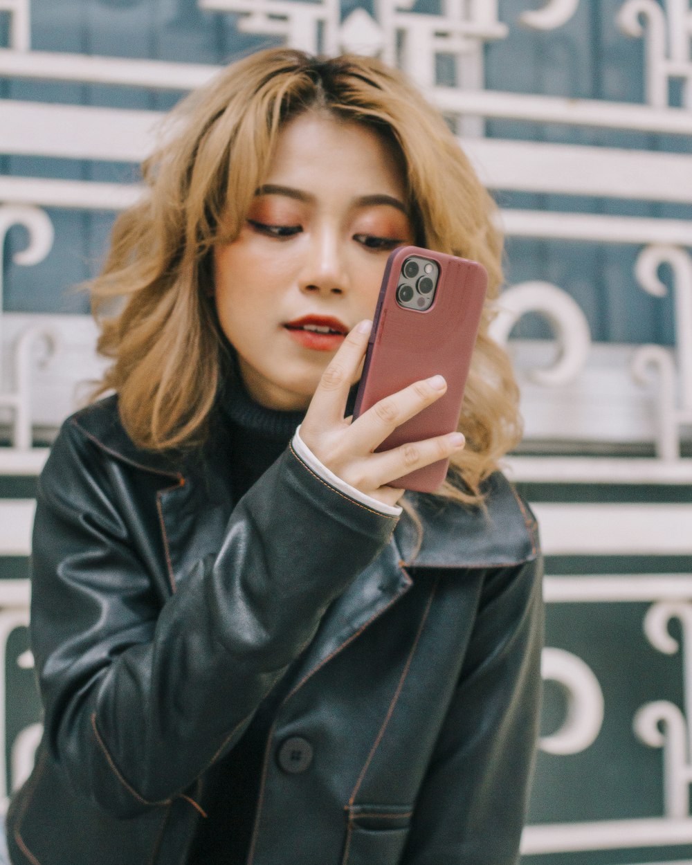 Mujer con chaqueta de cuero negro sosteniendo iPhone