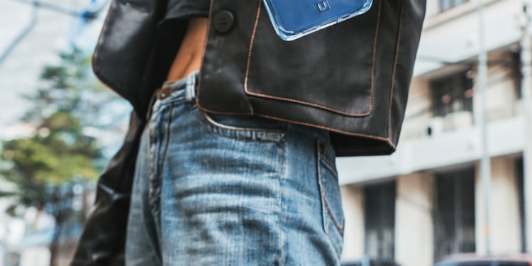 woman in black leather jacket holding blue iphone case