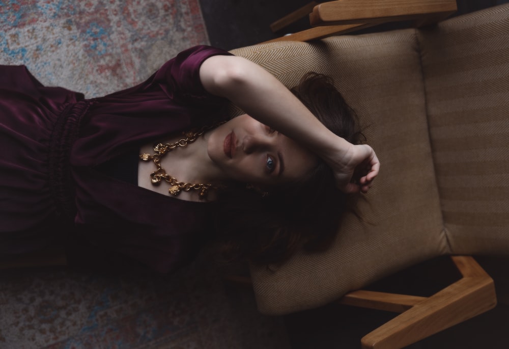 woman in purple dress lying on brown couch