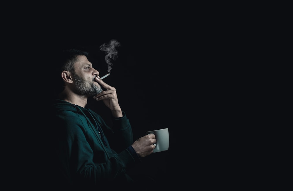 uomo in camicia nera a maniche lunghe fumante