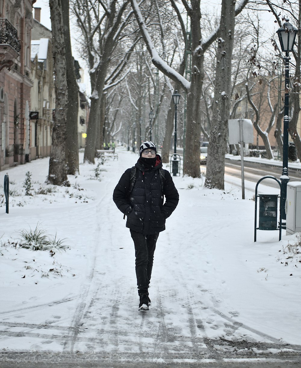 man in black jacket walking on snow covered ground during daytime