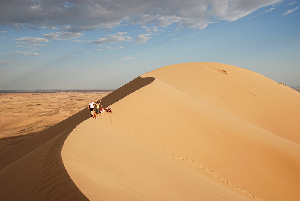 person in white shirt and black pants walking on brown sand during daytime