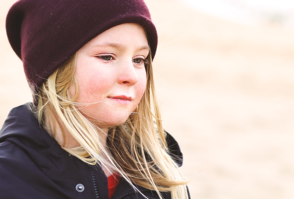 woman in black jacket and red knit cap