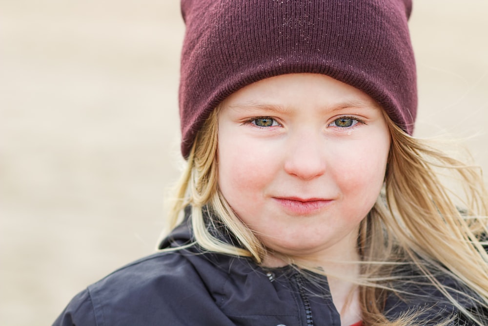 girl in black jacket wearing red knit cap