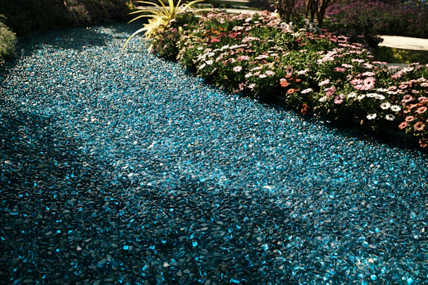 A pathway made with sparkling broken marble pieces winding through a green garden.