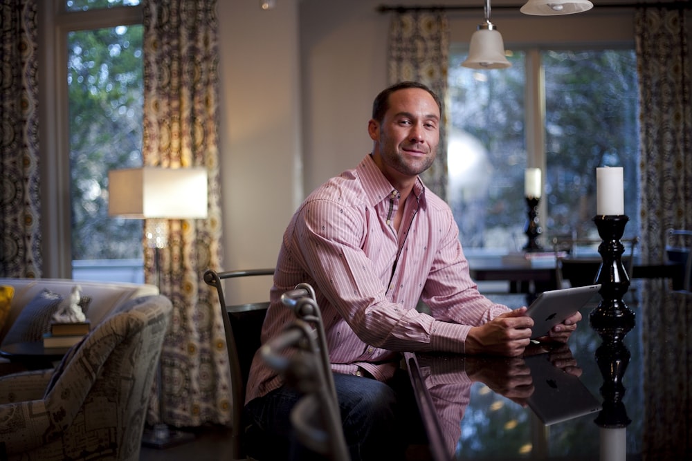 man in pink and white pinstripe dress shirt sitting on chair