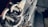 A close-up view of heavy-duty metal rings and thick, durable fabric straps, likely part of a harness or industrial equipment. The lighting creates a stark contrast, highlighting the textures and metallic surfaces.