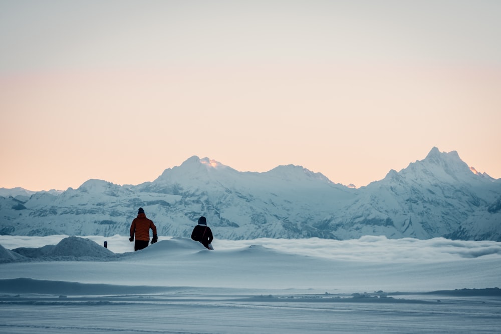 person in black jacket and black pants sitting on snow covered ground during daytime