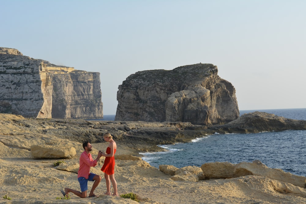 woman in red tank top standing on seashore during daytime