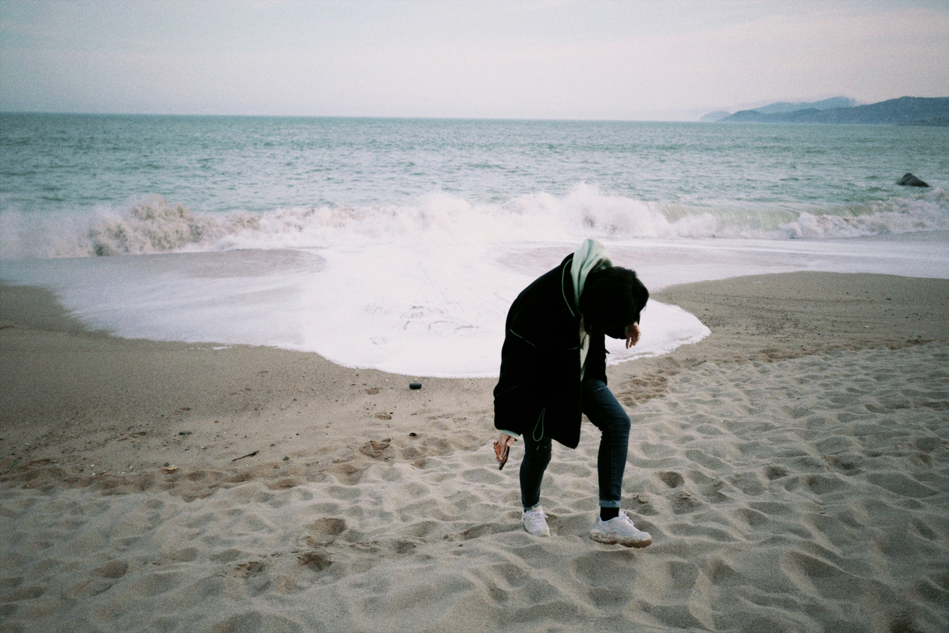 person in black jacket walking on beach during daytime
