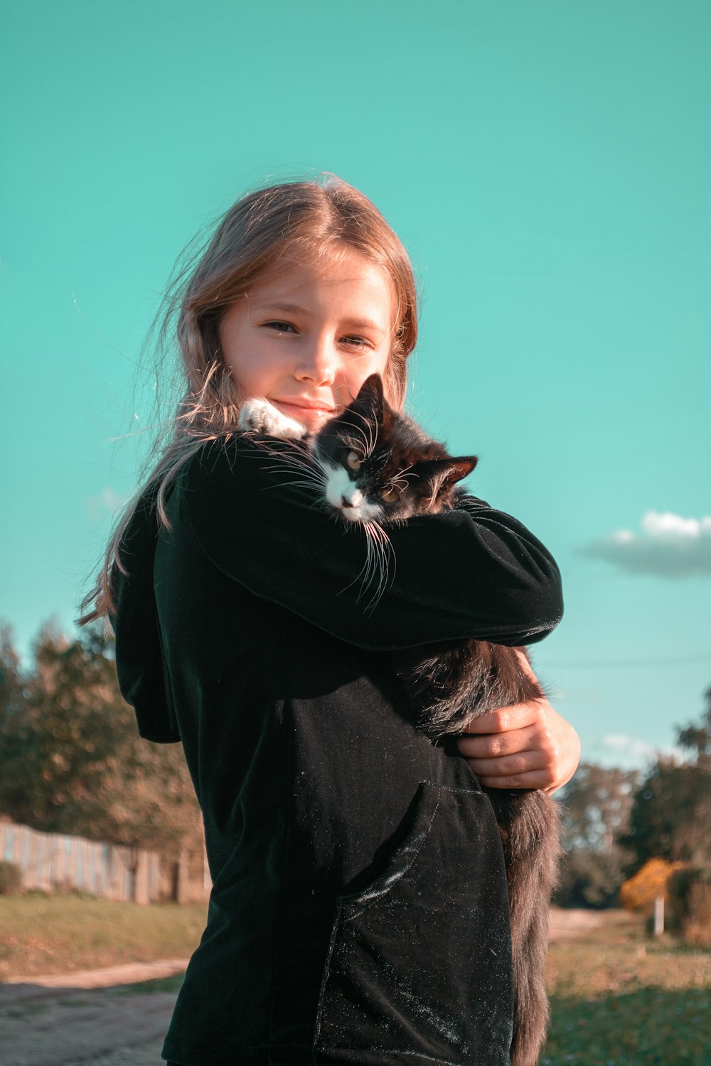 woman in black long sleeve shirt holding white and black cat