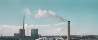 An industrial fossil fuel power plant with smokestacks emitting steam.