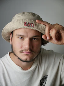 A minimalist beige bucket hat displayed against a soft pastel background.