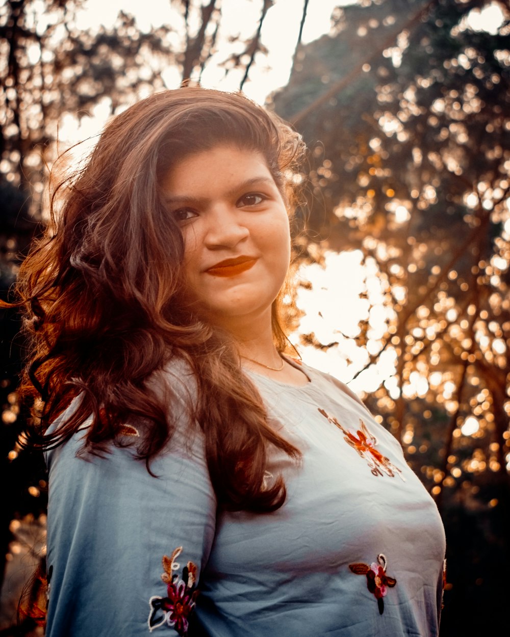 woman in white shirt standing under tree