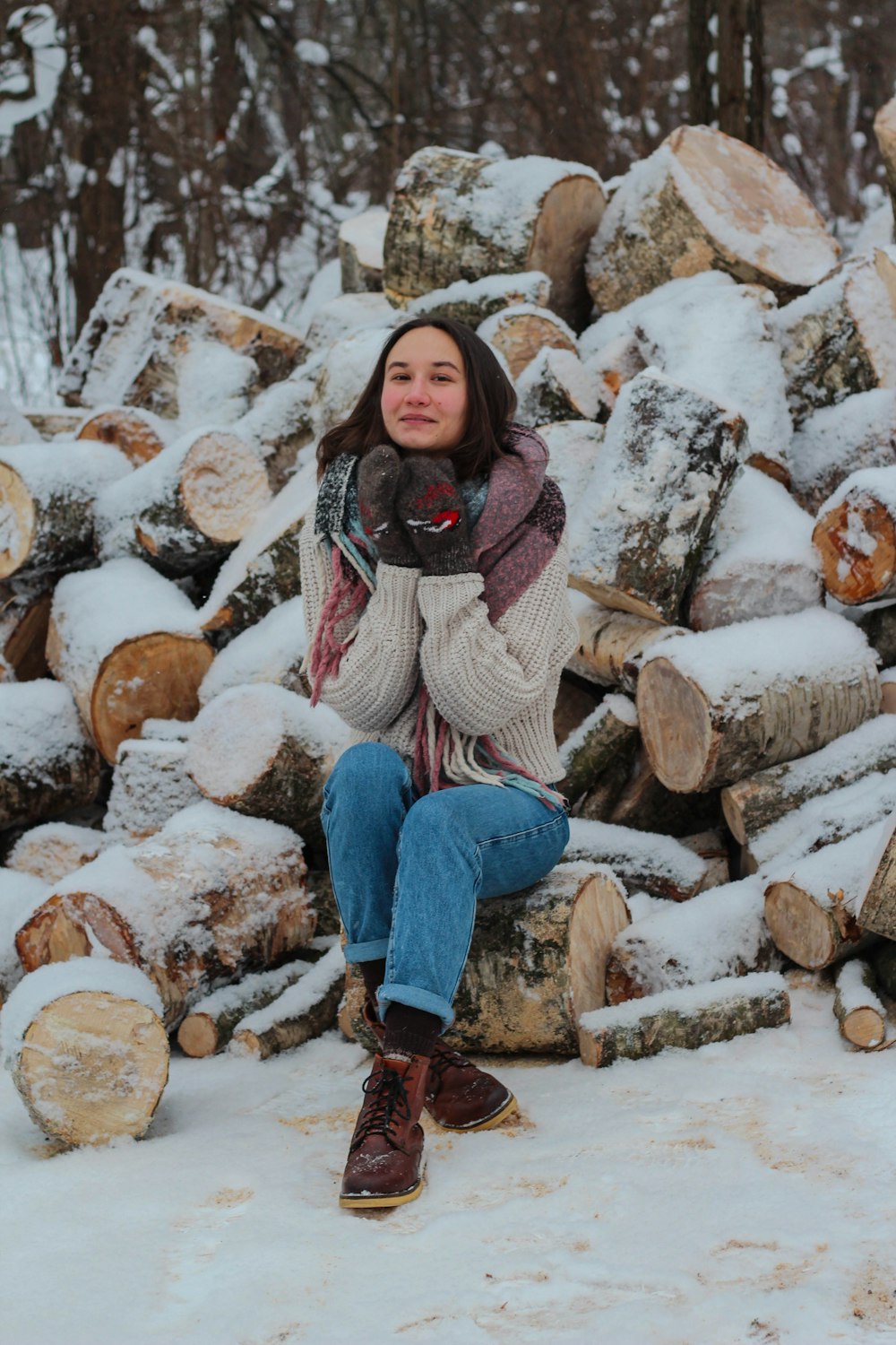 woman in brown sweater and blue denim jeans sitting on brown rock during daytime