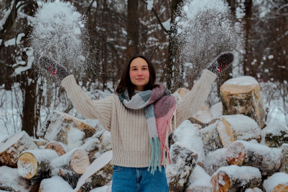 woman in white sweater and blue denim jeans standing on snow covered ground during daytime