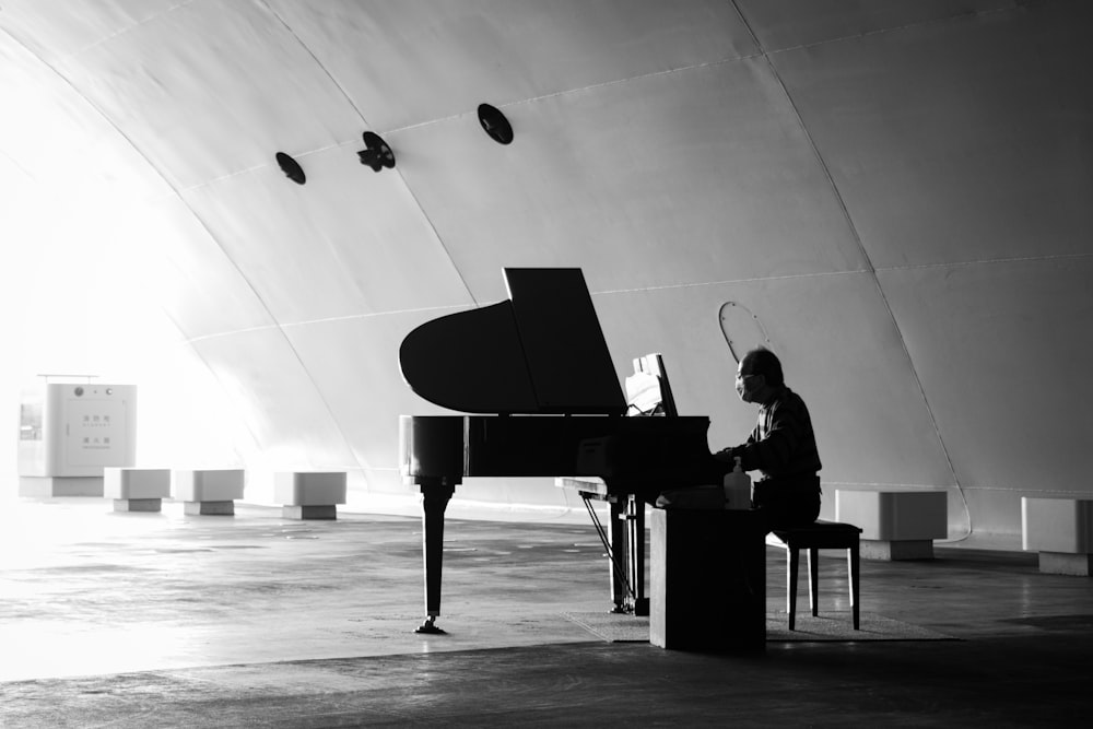 grayscale photo of man playing piano