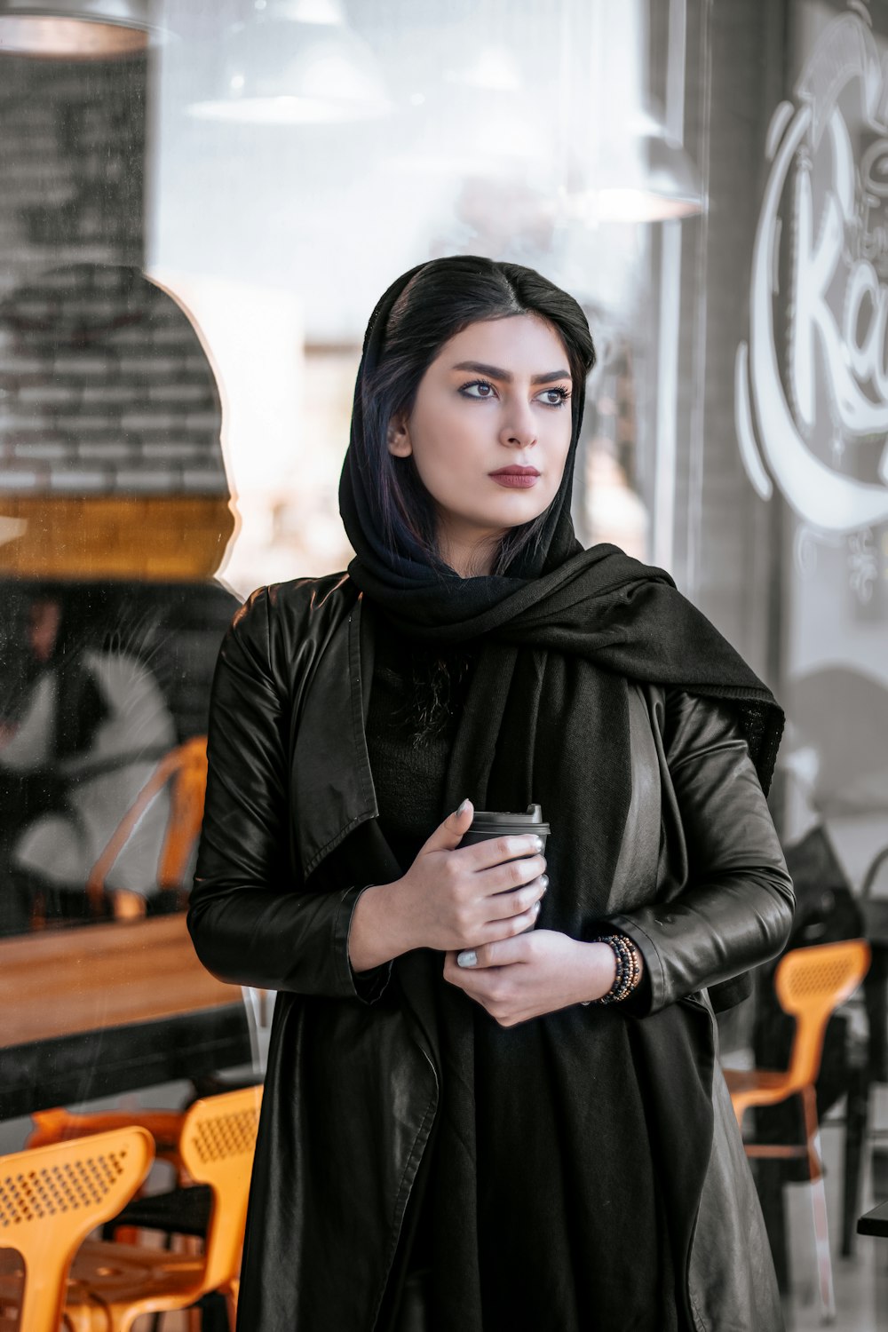 woman in black leather jacket holding black ceramic mug