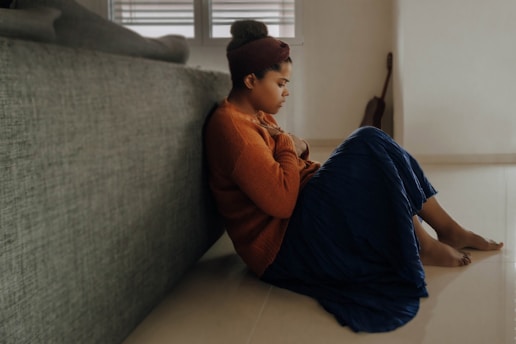Mulher triste e pensativa de blusa de lã laranja com a mão no peito