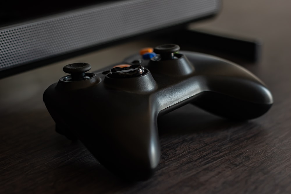 black xbox game controller on brown wooden table