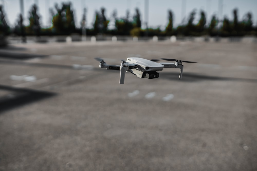 drone branco e preto no solo de concreto cinza durante o dia