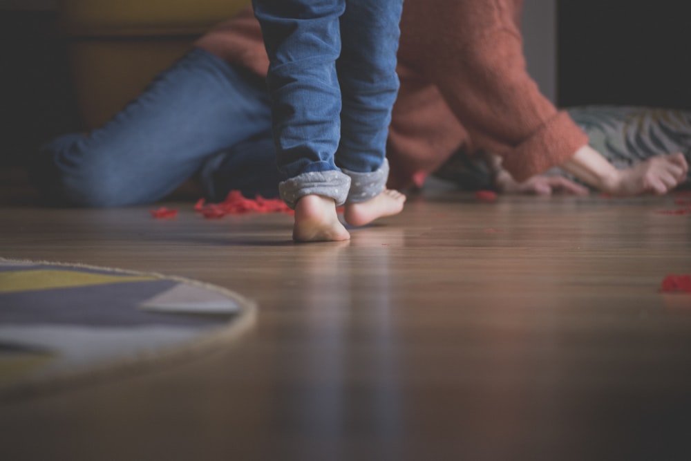 person in blue denim jeans sitting on brown wooden floor