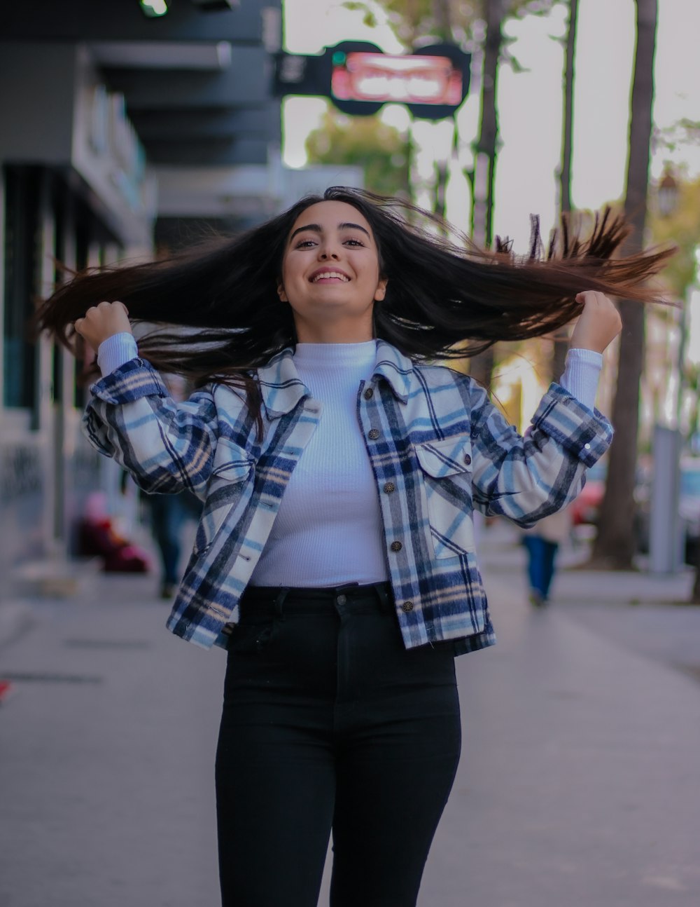 woman in white and black plaid button up shirt and black pants standing on sidewalk during