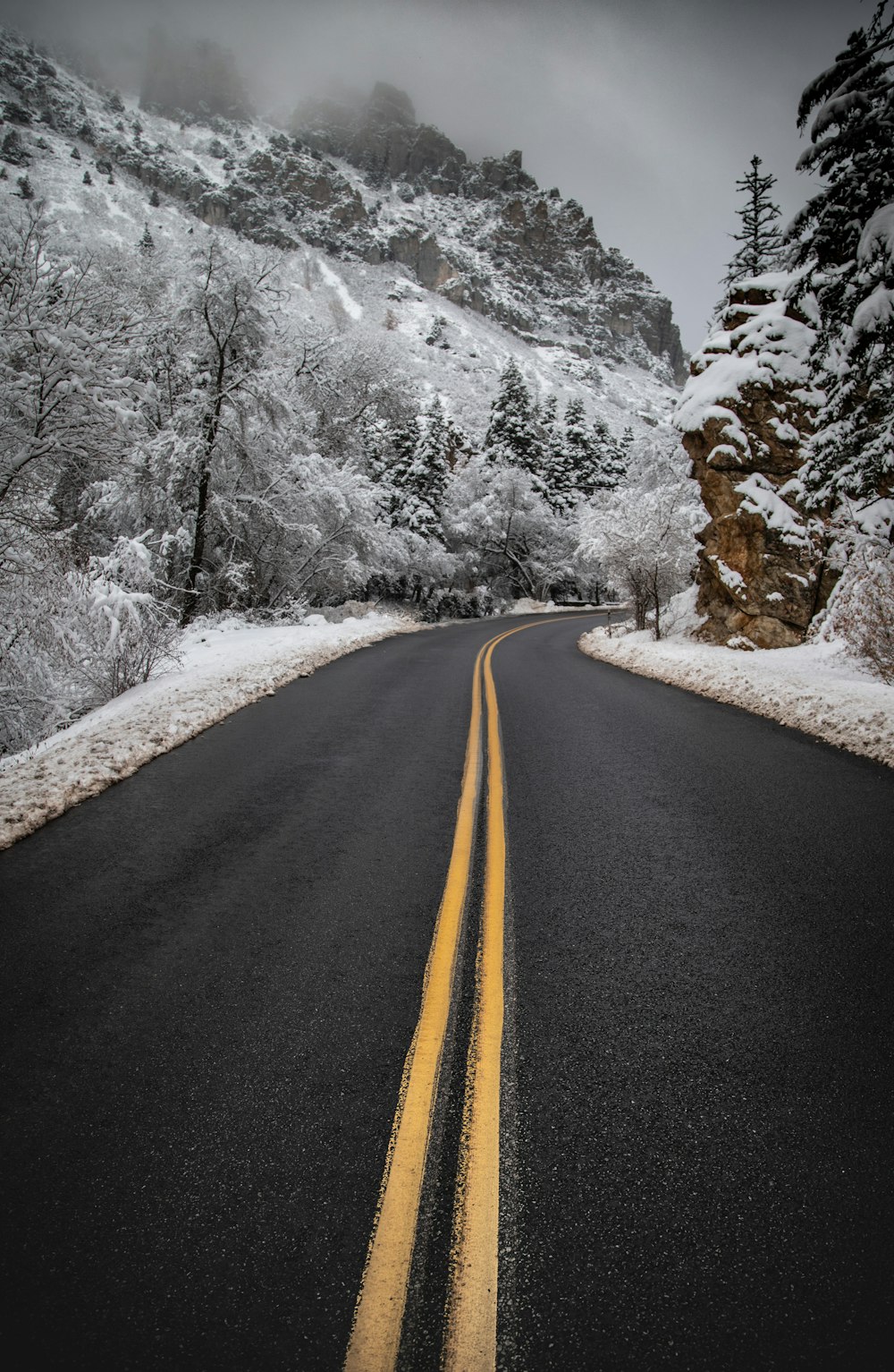 black asphalt road near snow covered mountain during daytime