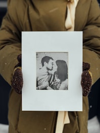 A close-up of hands holding a faded photograph of a historical Argentine event.